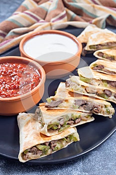 Mexican fajita quesadilla with pieces of beef steak, green bell pepper, onion and cheese, on plate