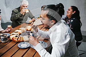 Mexican family eating Rosca de Reyes or Epiphany cake, Roscon de reyes with traditional mexican chocolate cup in Mexico