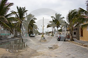 Mexican fishing village street during the rainy season with cars parked along the sides and bag of garbage in the middle of the st