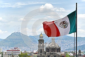 Mexican flag waving in the wind, close-up, Mexico City centre and Santo Domingo church in the background