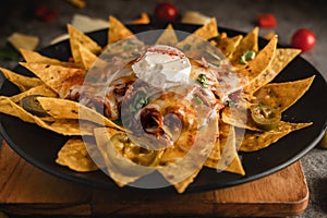 Mexican food background of chicken tortilla nachos in black dish in dark tone, selective focused