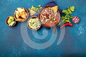 Mexican food concept background with chile black bean soup, guacamole and nachos totopos. Top view