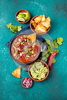 Mexican food concept background with chile black bean soup, guacamole and nachos totopos. Top view