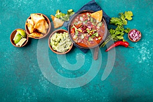 Mexican food concept background with chile black bean soup, guacamole and nachos totopos. Top view