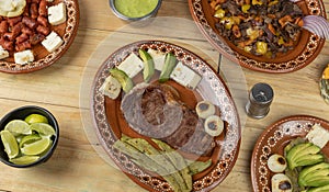 Mexican food, cut of meat served on a plate with nopal, avocado and onion on a wooden table photo