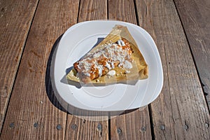 Mexican food dish with fried tamal with sauce, cream and cheese