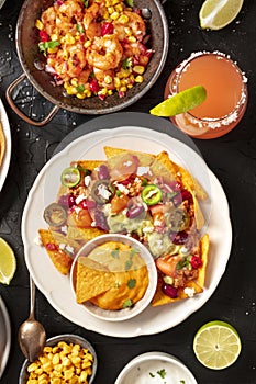 Mexican food, a flat lay on a black background. Nachos, shrimps, Paloma cocktails,