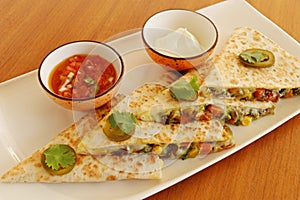 Mexican food quesadilla, spicy cooked chicken and vegetable stuffed in tortilla bread with cheese, guacamole, tomato salsa and