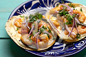 Mexican food. Shrimp tacos with melted cheese and poblano pepper called gobernador on turquoise background photo