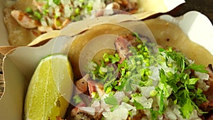 Mexican food smoked pork belly and chicken with onion cilantro and lime in tortilla taco close up