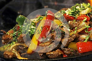mexican food smoking chicken and beef fajitas on hot sizzling plate