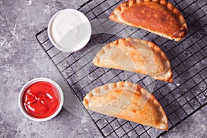 Mexican fried meat pies empanadas cheburek on the baking rack with dips