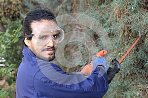 Mexican gardener trimming a bush