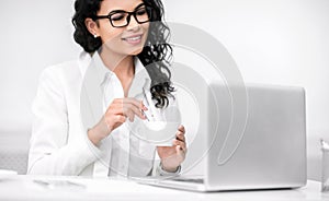 Mexican girl holding cup of cofee working in office