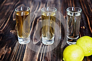 Mexican gold and silver tequila and lime on wood background