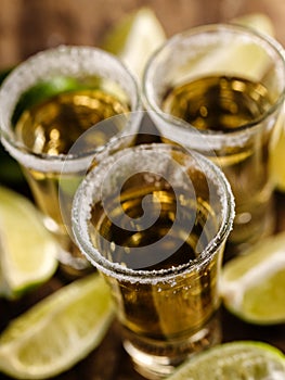 Mexican Gold Tequila with lime and salt on wooden table