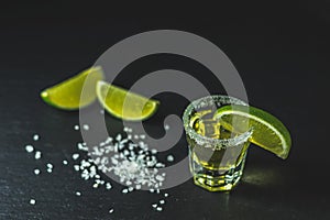 Mexican Gold Tequila shot with lime and salt on black stone table surface