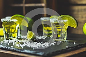 Mexican Gold Tequila shot with lime and salt on black stone table surface