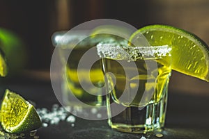 Mexican Gold Tequila shot with lime and salt on black stone table surface