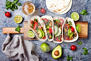 Mexican grilled chicken tacos with avocado, tomato, onion on rustic stone table. Recipe for Cinco de Mayo party. photo
