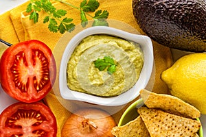 Mexican guacamole with ingredients and nachos