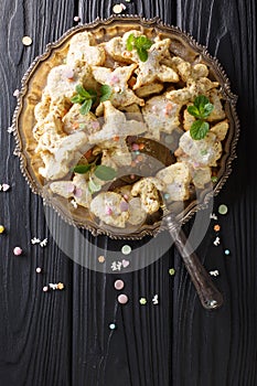 Mexican hojarascas curly festive cookies with pecans closeup on a dish. Vertical top view photo