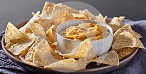 Mexican hot queso cheese dip with corn tortilla chips on plate