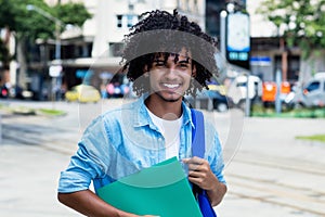 Mexican male student with long curly hair outdoor in city