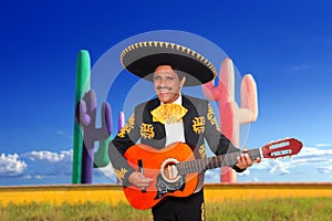 Mexican mariachi charro playing guitar in cactus