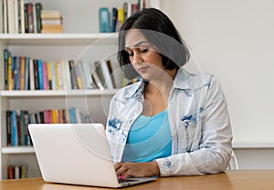 Mexican mature adult woman working with concentration at computer