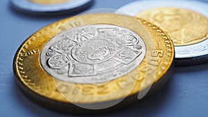 Mexican money lies on blue surface. Coin of 10 pesos closeup. Peso of Mexico. News about economy or currency. Loan and credit.