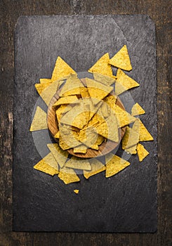 Mexican nacho in wooden bowl on dark rustic background top view