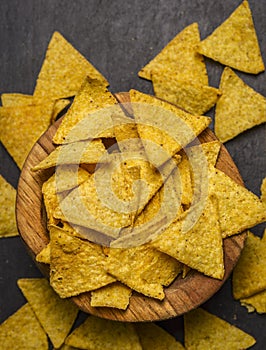 Mexican nacho in a wooden bowl on dark rustic background top view