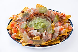 Mexican nachos with beef, guacamole, cheese sauce, peppers, tomato and onion in plate isolated