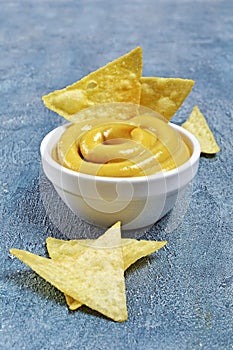 Mexican nachos chips with cheese sauce or dip in white bowl