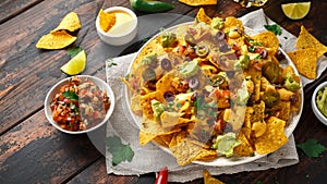 Mexican nachos tortilla chips with olives, jalapeno, guacamole, tomatoes salsa, cheese dipand beer.