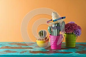 Mexican party concept with cactus and sombrero hat on wooden blue table over colorful background. Cinco de Mayo holiday