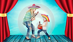 Mexican party. A small boy in a sombrero plays the guitar and sings a serenade for his mother.
