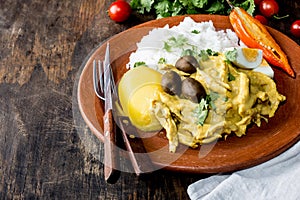 MEXICAN AND PERUVIAN CUISINE. Aji de gallina. Chicken aji de gallina with olives egg and rice on clay plate. Tipical photo