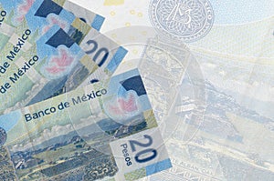 20 Mexican pesos bills lies in stack on background of big semi-transparent banknote. Abstract business background photo