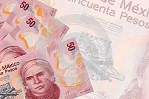 50 Mexican pesos bills lies in stack on background of big semi-transparent banknote. Abstract business background photo