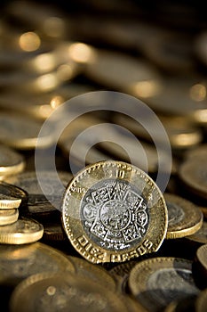 Mexican 10 pesos coin in the foreground, with many more coins in the background photo