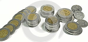 Mexican pesos, stacked coins of various denominations on white background