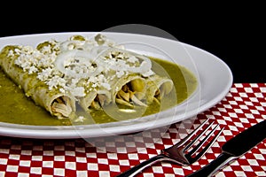 Mexican enchiladas with green sauce cheese and sour cream photo