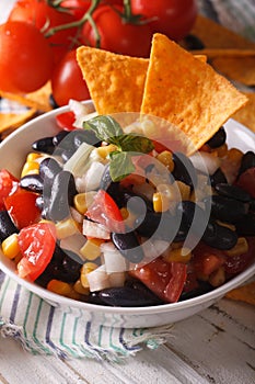 Mexican salsa with black beans and corn chips close up. Vertical