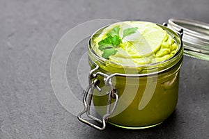 Mexican sauce guacamole in a jar on black stone background