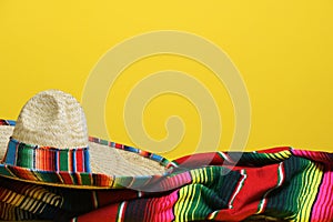 Mexican sombrero on a colorful serape blanket on a yellow background. Cinco de Mayo theme