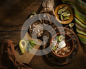 Mexican spicy soup with lime, tortilla, avocado and cream