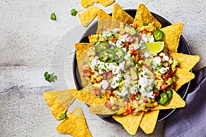 Mexican street corn salad with cheese and nachos chips in black plate, top view. Mexican food concept