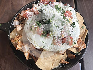 Mexican style breakfast, egg over avocado,salsa,chicken and chips